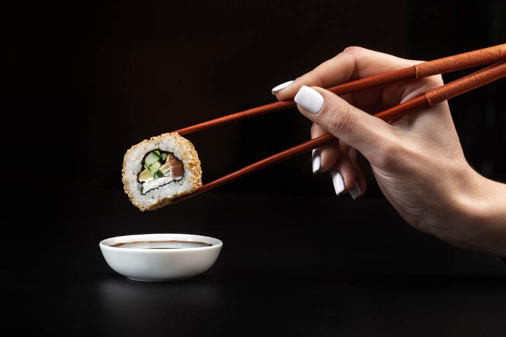 Sushi roll being dipped in soy sauce